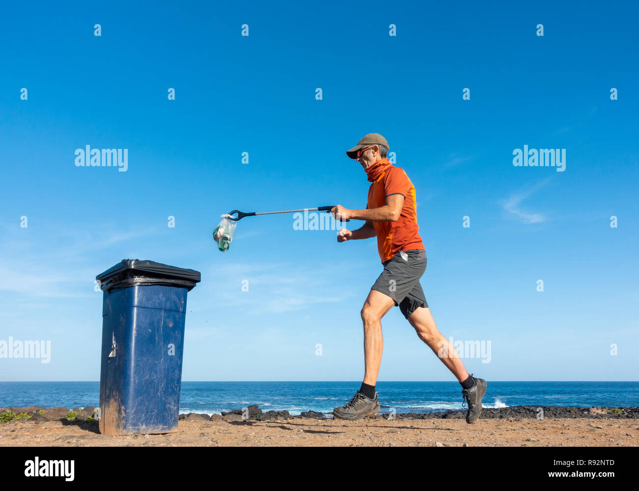 Un Plogger/jogger recueille des ordures en plastique de la plage durant son jogging Banque D'Images