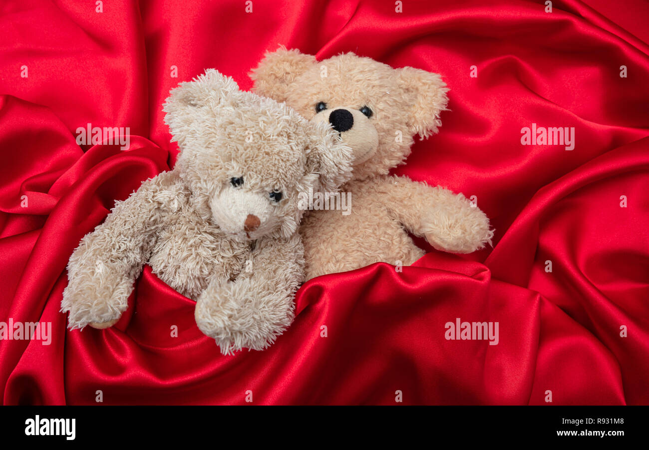 L'amour, la Saint-Valentin concept, bras. Deux ours en embrassant comme un couple au lit, fond satin rouge Banque D'Images