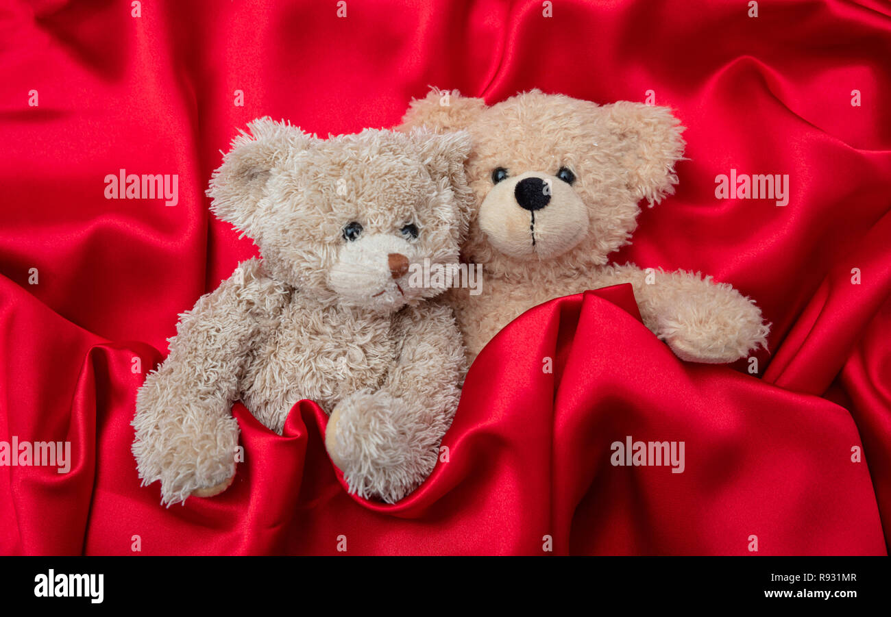 L'amour, la Saint-Valentin concept, bras. Deux ours en embrassant comme un couple au lit, fond satin rouge Banque D'Images
