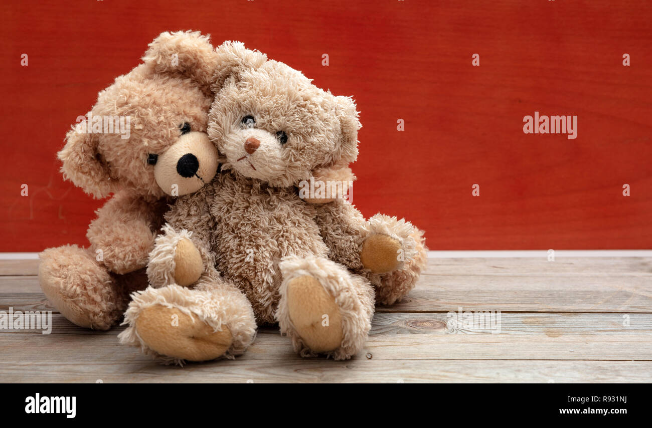 L'amour, l'amitié concept, bras. Deux ours en embrassant comme un couple sur un plancher en bois, red wall background, copiez l'espace. Banque D'Images