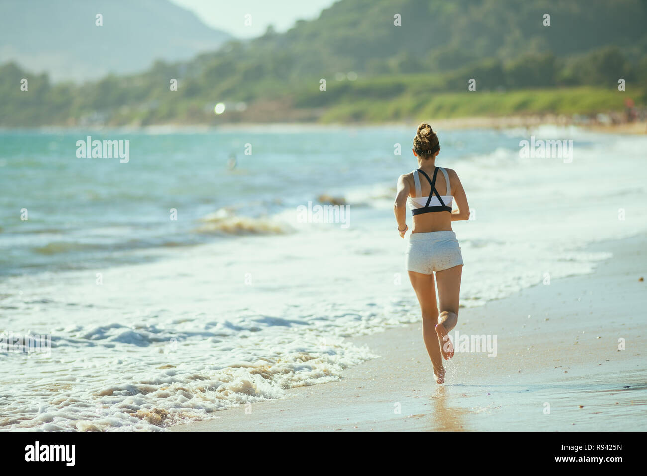 Vus de derrière, jeune femme en vêtements de sport de remise en forme sur la côte de l'océan dans la soirée le jogging. fatigué de routage de tous les jours quelque chose de 30 ans f Banque D'Images