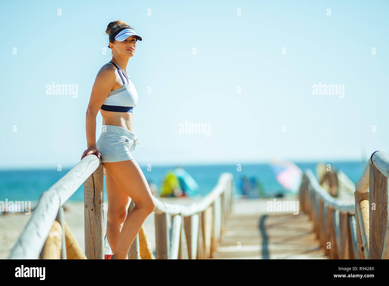 Fit sports femme en vêtements de fitness sur la plage à la recherche dans la distance. Il y a tant de différentes manières de rester active pendant que sur la plage. Les jeunes adul Banque D'Images