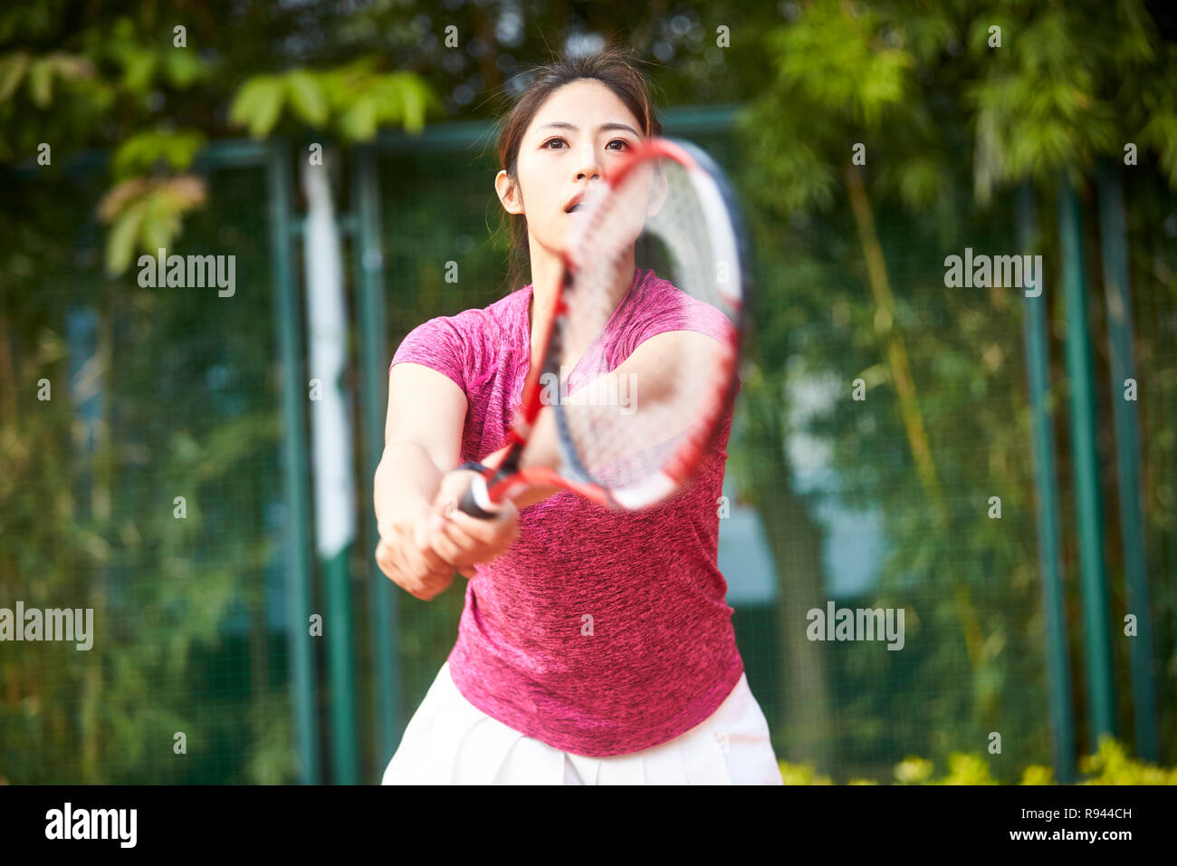 Young Asian woman playing tennis outdoors Banque D'Images