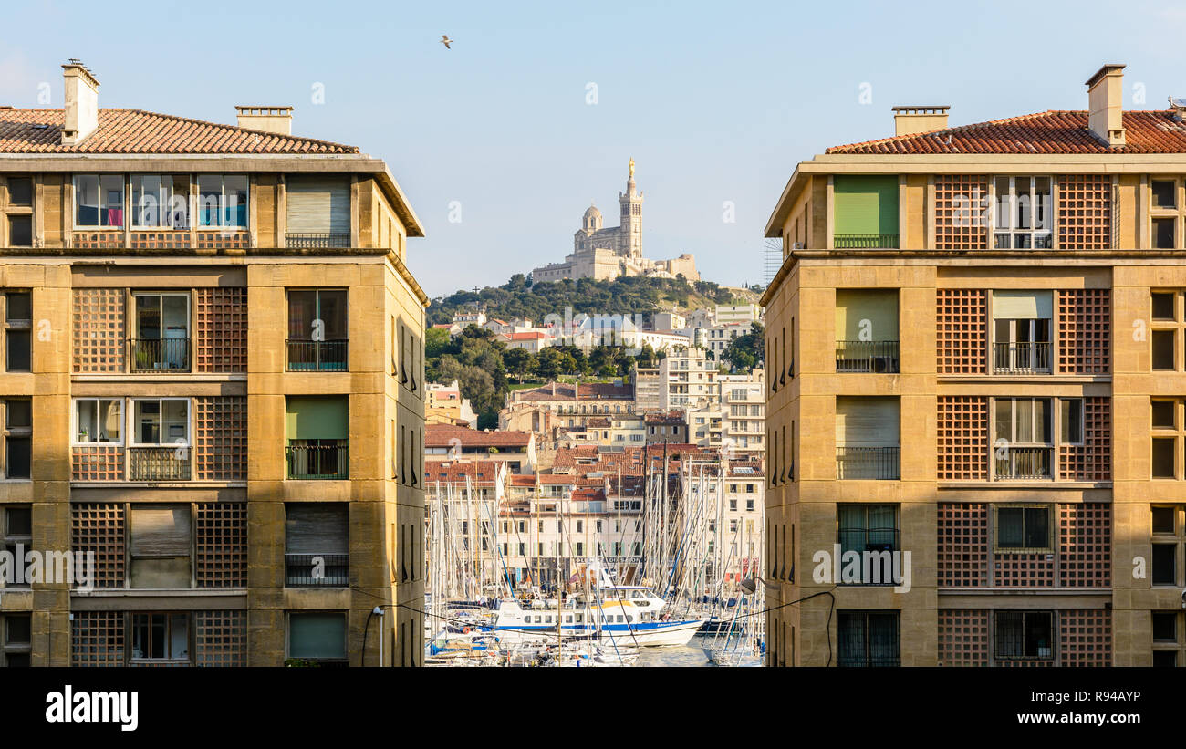 Le Vieux Port de Marseille, France, vu entre bâtiments résidentiels avec Notre-Dame de la garde en haut d'une colline dans l'arrière-plan. Banque D'Images