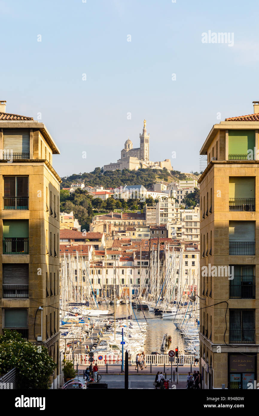 Le Vieux Port de Marseille, France, vu entre bâtiments résidentiels avec Notre-Dame de la garde en haut d'une colline dans l'arrière-plan. Banque D'Images