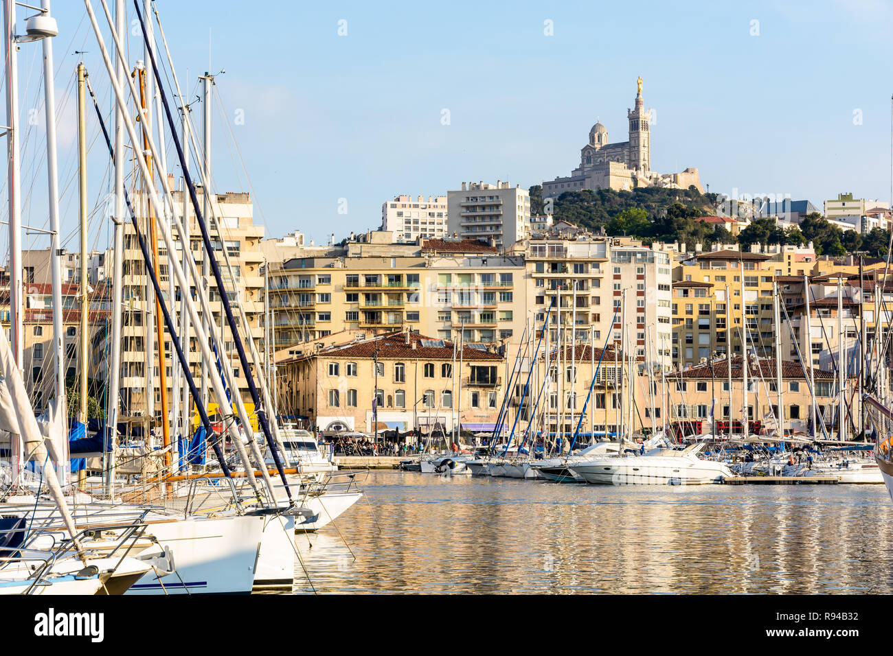 Le Vieux Port de Marseille, France, avec les bateaux et voiliers amarrés dans le port de plaisance et la basilique Notre-Dame de la garde en haut de la colline au coucher du soleil Banque D'Images