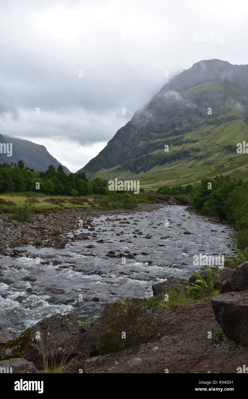 La rivière qui coule à travers la vallée de l'Europe de la chaîne de montagnes Glencoe dans les Highlands écossais. Pris sur un ciel couvert et pluie d'août 24. Banque D'Images