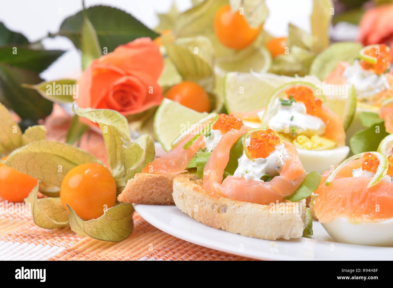 Les moitiés d'oeufs de saumon fumé et caviar de truite sur le fromage à la crème, décoré par des bandes d'écorce de lime Banque D'Images