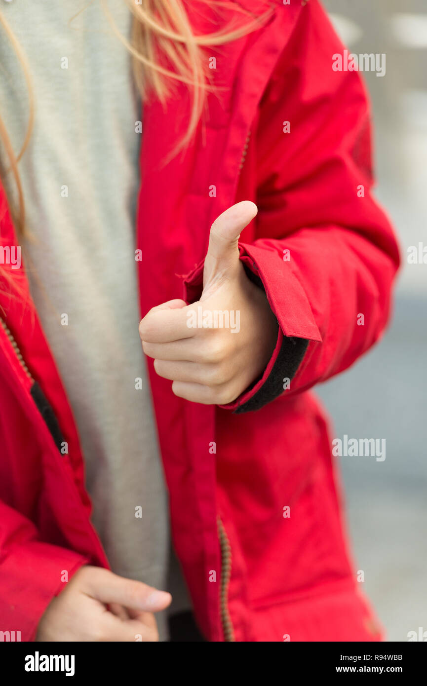 Main de bébé présente Thumbs up geste. Kid porter veste chaude montrer geste d'accord ou d'accepter. Elle aime ça. Thumb up sens comme geste et de l'accord. Bravo et comme concept. Banque D'Images