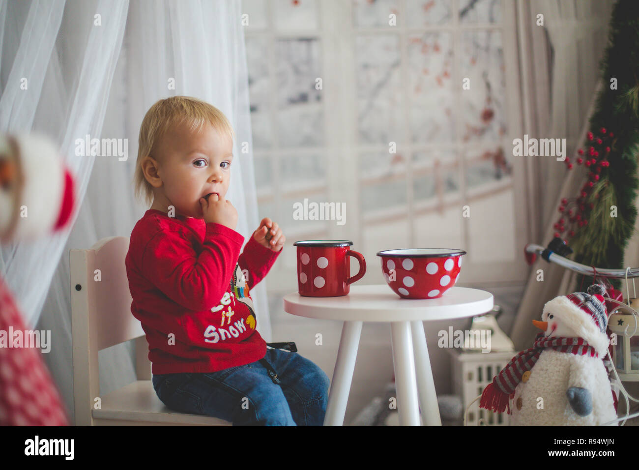 Petit bébé garçon, boire du thé et manger des biscuits avec peluche sur un jour de neige dans la maison confortable Banque D'Images