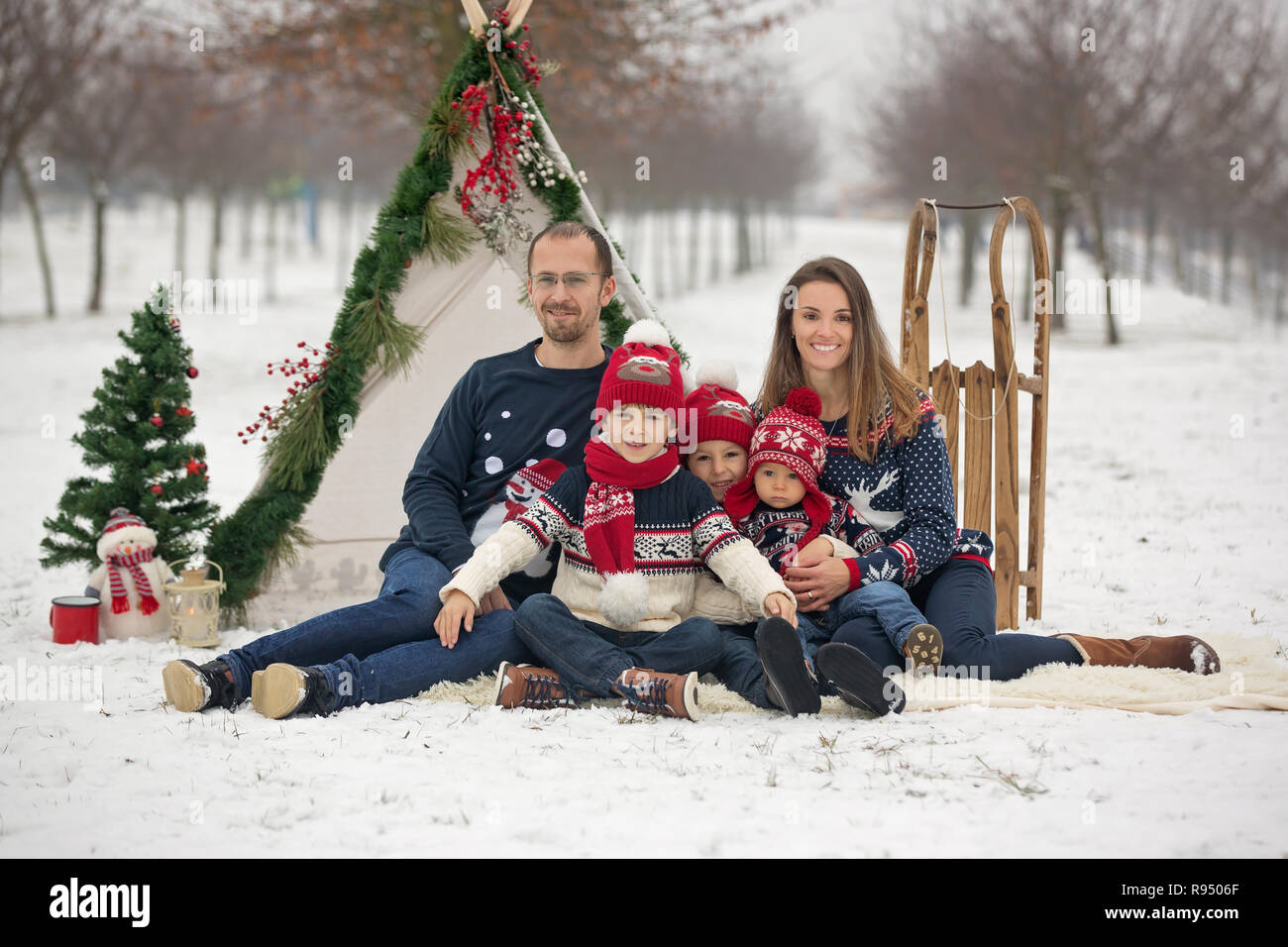 Une famille heureuse avec des enfants, s'amuser dehors dans la neige à Noël, jouer avec le traîneau, tipi et décoration de Noël Banque D'Images