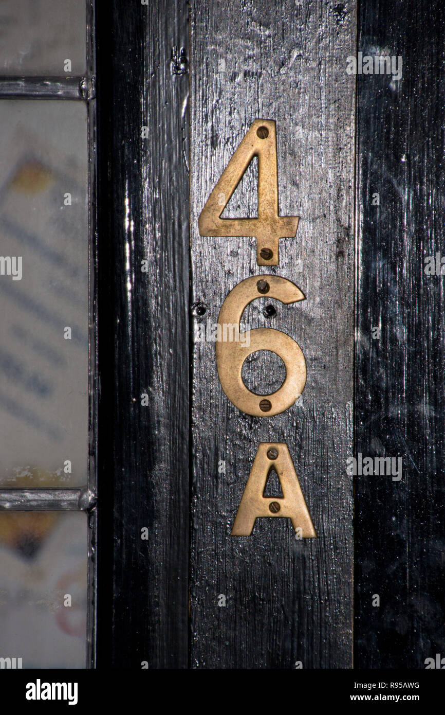 Le numéro 46A en laiton sur une porte en bois noir Banque D'Images