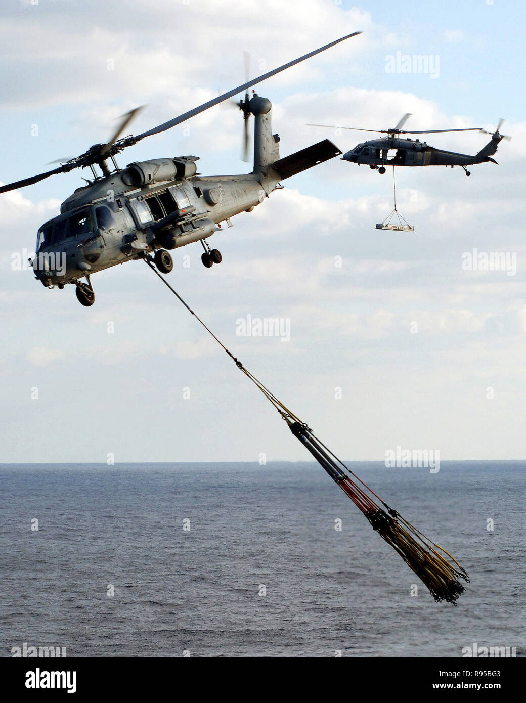 Un hélicoptère HH-60H Seahawk Hélicoptère, de l'Escadron anti-sous-onze  (HS-11), s'éloigne de l'envol de la porte-avions nucléaire USS Enterprise  (CVN 65) avec plusieurs élingues reconstitution vide en remorque tandis  qu'un hélicoptère Seahawk MH-60S,