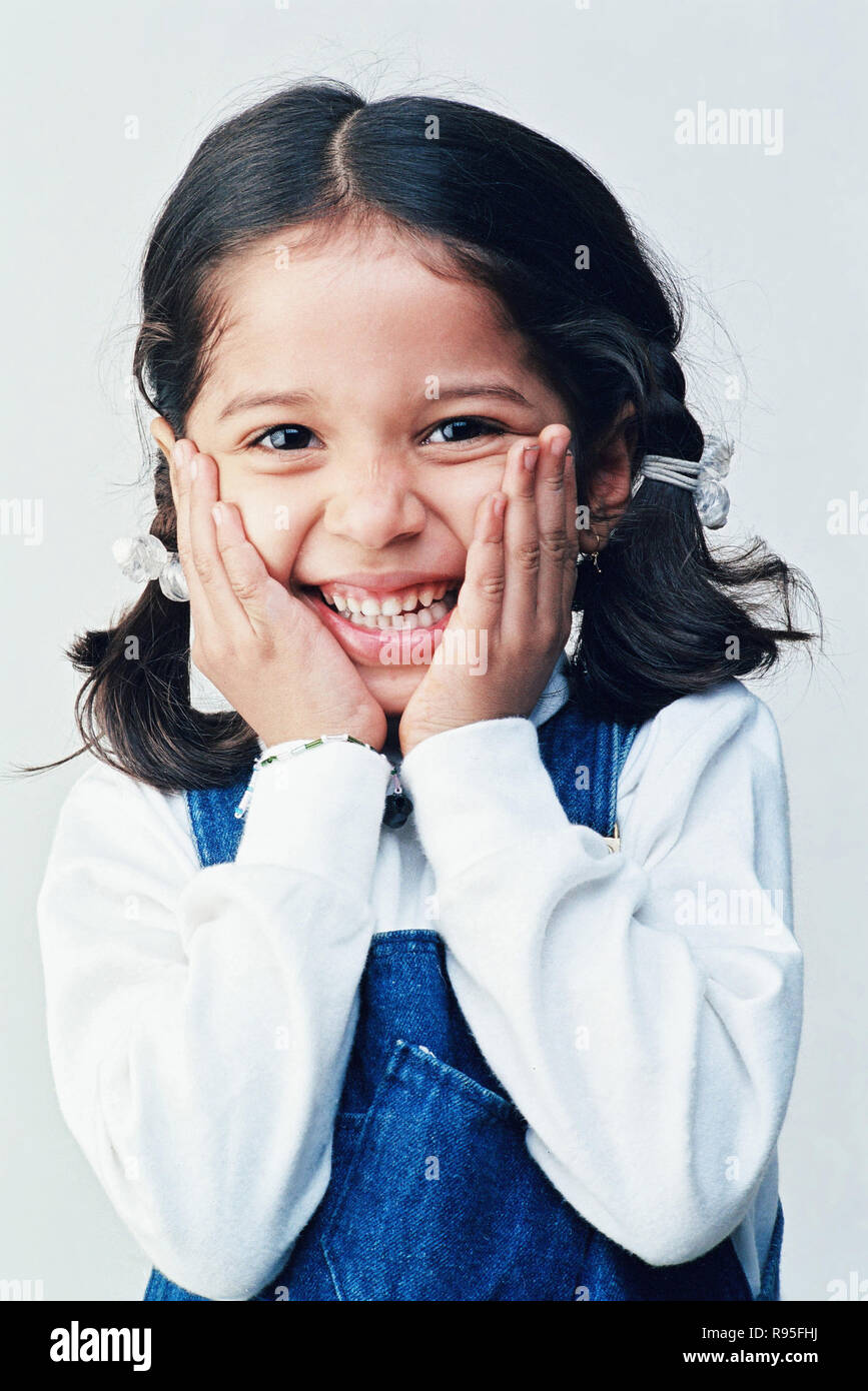 Fille, mains sur le visage, rire, regarder l'appareil photo Banque D'Images