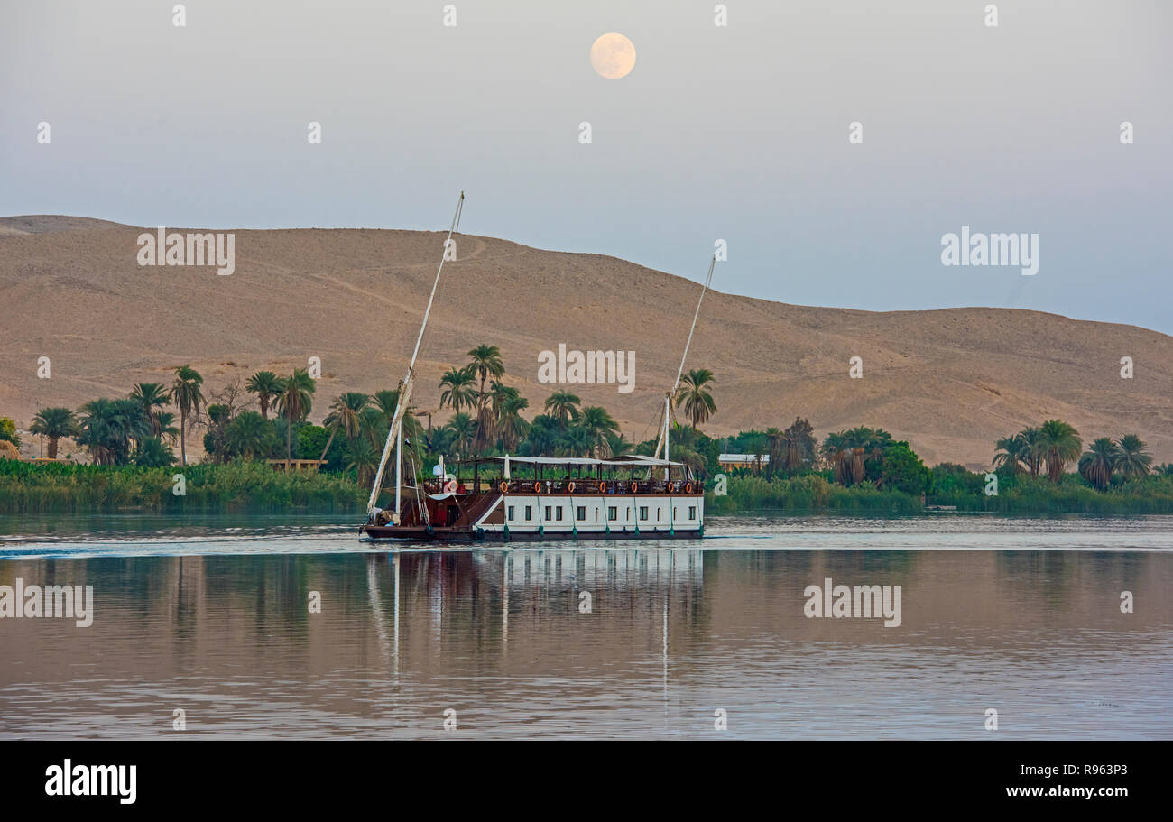 Grande rivière traditionnel égyptien de luxe dahabeya bateau naviguant sur le Nil avec la réflexion et la lune dans le ciel Banque D'Images