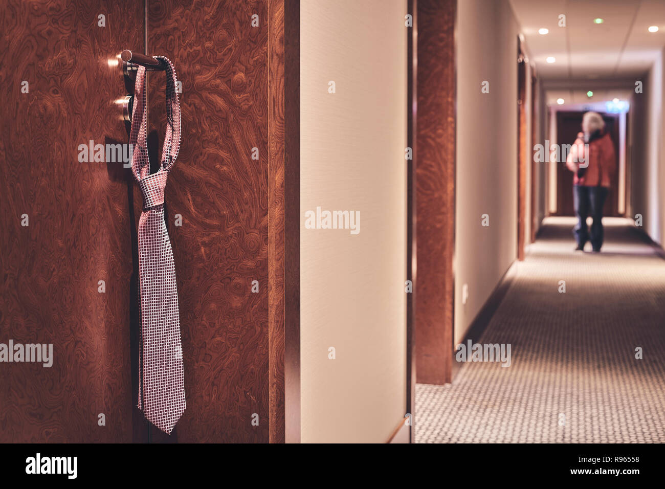 Tie accroché sur une poignée de porte fermée de l'hôtel, ne pas déranger signe informel rétro, harmonisation des couleurs appliquées, selective focus. Banque D'Images