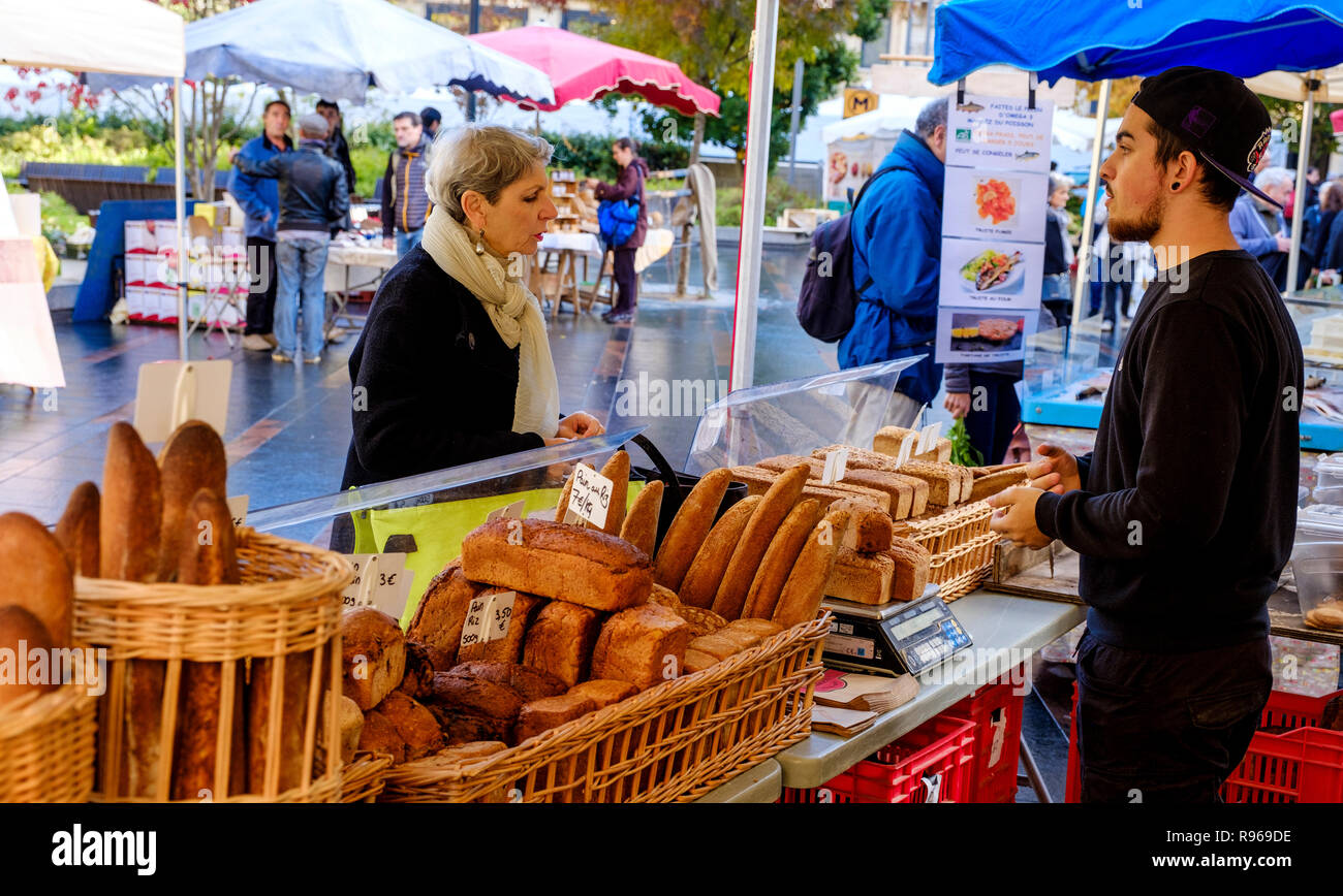 Un client acheter du pain à un artisan boulanger stall dans un marché de rue de la Place Charles de Gaulle, Toulouse, France Banque D'Images