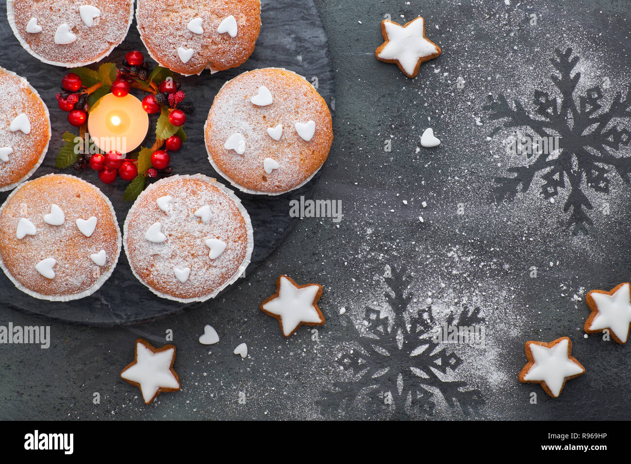 Vue du dessus de la table avec du sucre saupoudré de muffins et biscuits de Noël étoiles sur fond texturé noir Banque D'Images