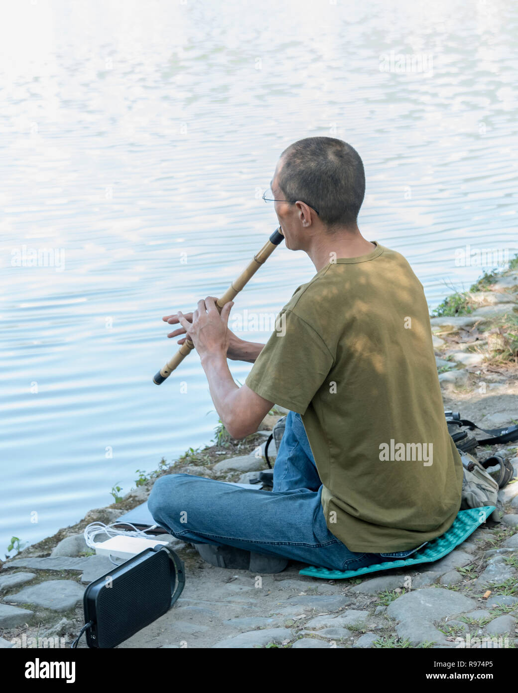 Le joueur de flûte sur les rives du lac South, Hongcun Ancient Town, Lixian, Anhui, Chine Banque D'Images