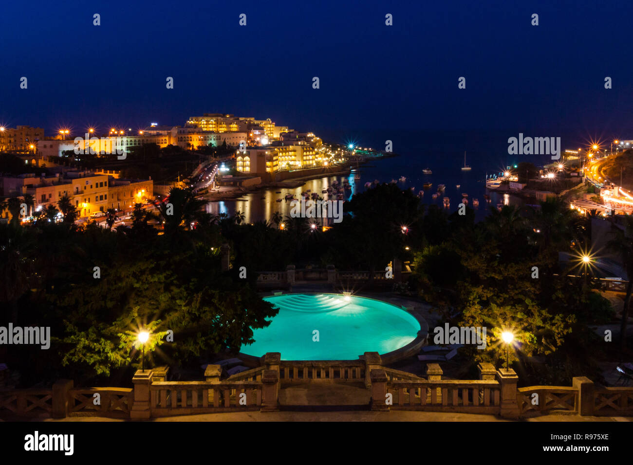 Vue de Saint George's Bay seafront lumières par nuit, avec un bleu piscine de luxe et bateaux et yachts ancrés. St Julian's (San Giljan), la Région du Centre, à Malte. En soirée, quartier de Paceville. Banque D'Images