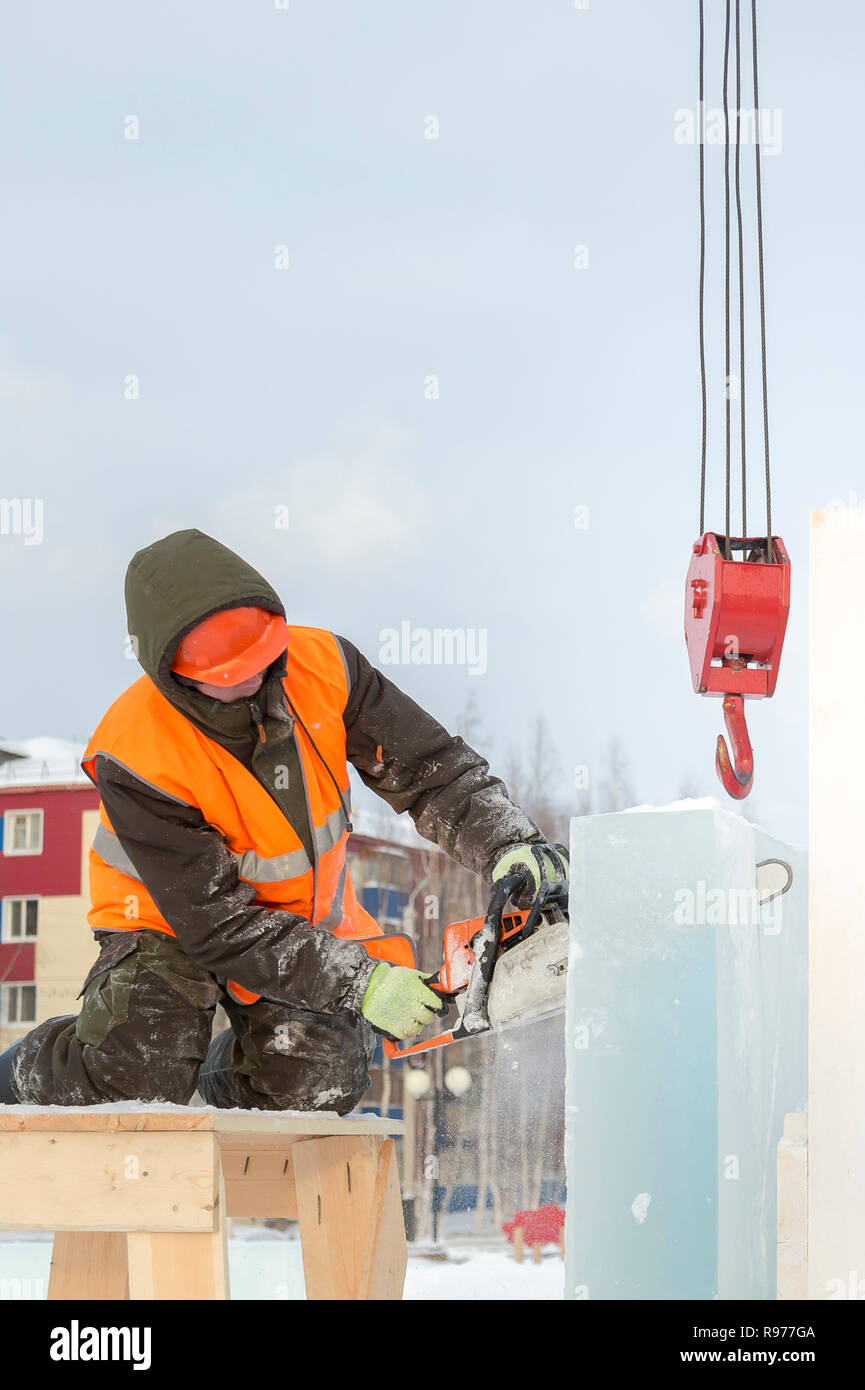 Portrait d'un ajusteur slinger dans un casque et gilet orange sur le déchargement des plaques de glace Banque D'Images