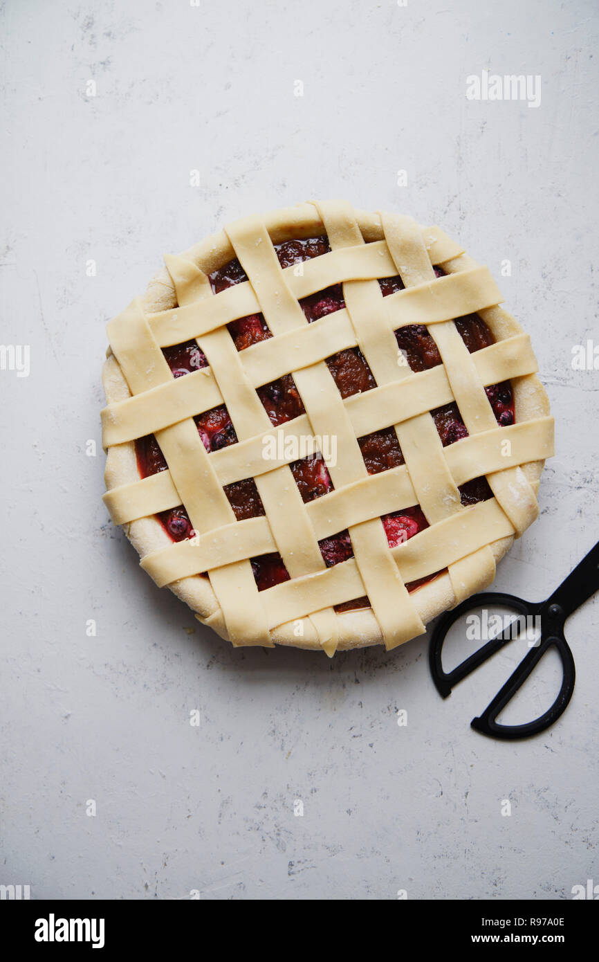 Tarte aux fruits crus un treillis décoration sur le haut. Arrière-plan de béton, processus de cuisson. Banque D'Images