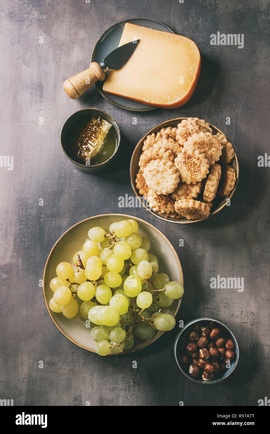 Snack-vin. Le fromage, raisins, noix, fromage craquelins Biscuits, d'abeilles avec couteau sur fond texture sombre. Mise à plat, de l'espace Banque D'Images