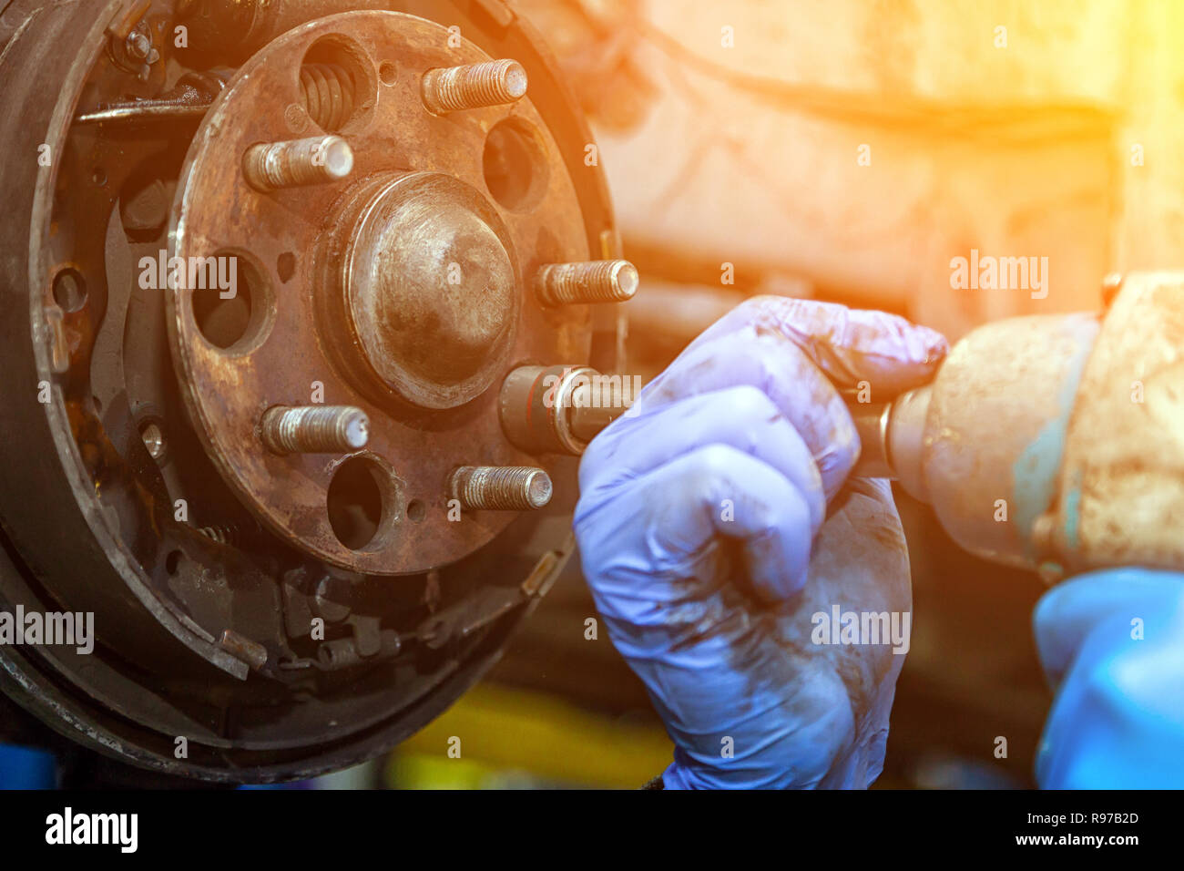 Close-up le remplacement de l'ancien disque de frein avant, Étrier de frein et l'écrou de moyeu sur une voiture posée sur un pont avec une clé pneumatique dans un atelier de réparation de voiture. Au Banque D'Images