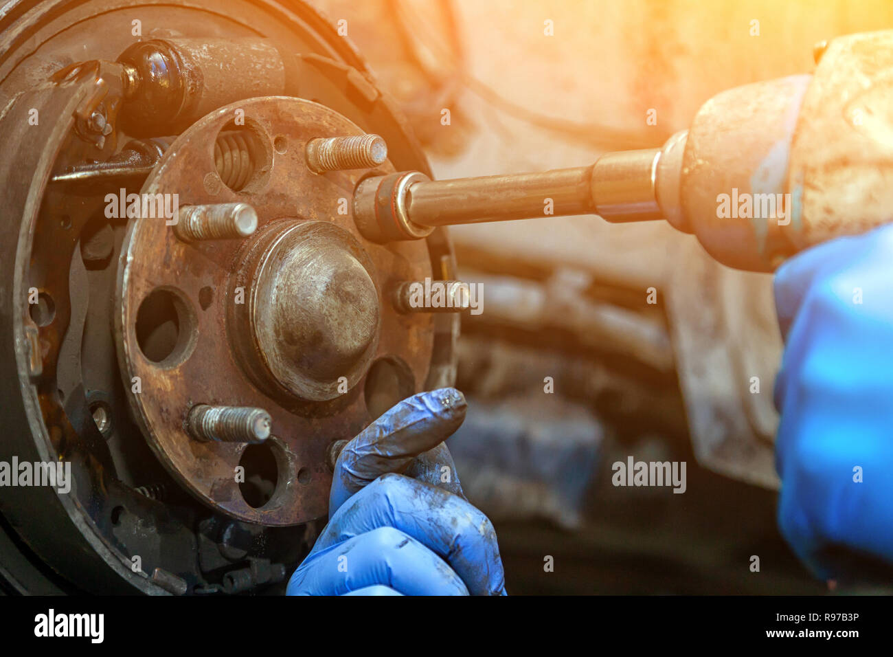 Close-up le remplacement de l'ancien disque de frein avant, Étrier de frein et l'écrou de moyeu sur une voiture posée sur un pont avec une clé pneumatique dans un atelier de réparation de voiture. Au Banque D'Images