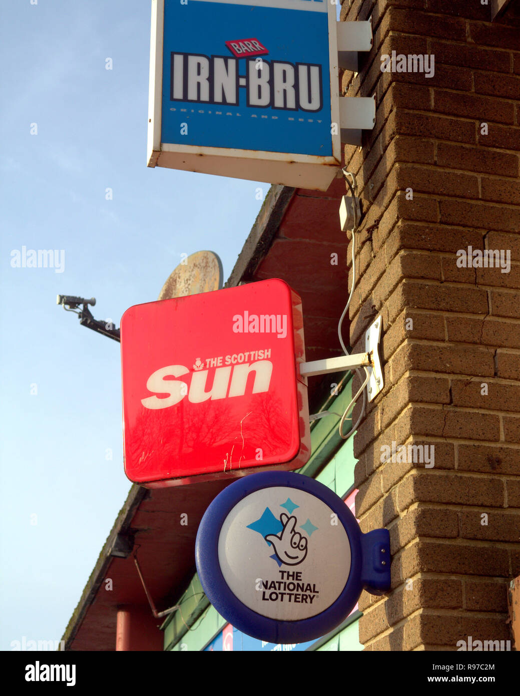 Marchand de panneau publicitaire pour irn bru IRN-BRU , le scottish sun, la loterie nationale, pour un magasin appelé news et booze ciel bleu Banque D'Images