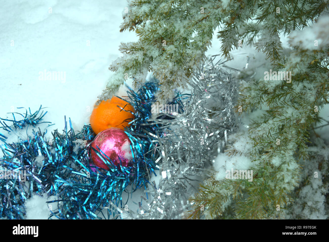 Arrière-plan de l'an avec une branche d'un arbre de Noël, les jouets et la mandarine sur la neige Banque D'Images