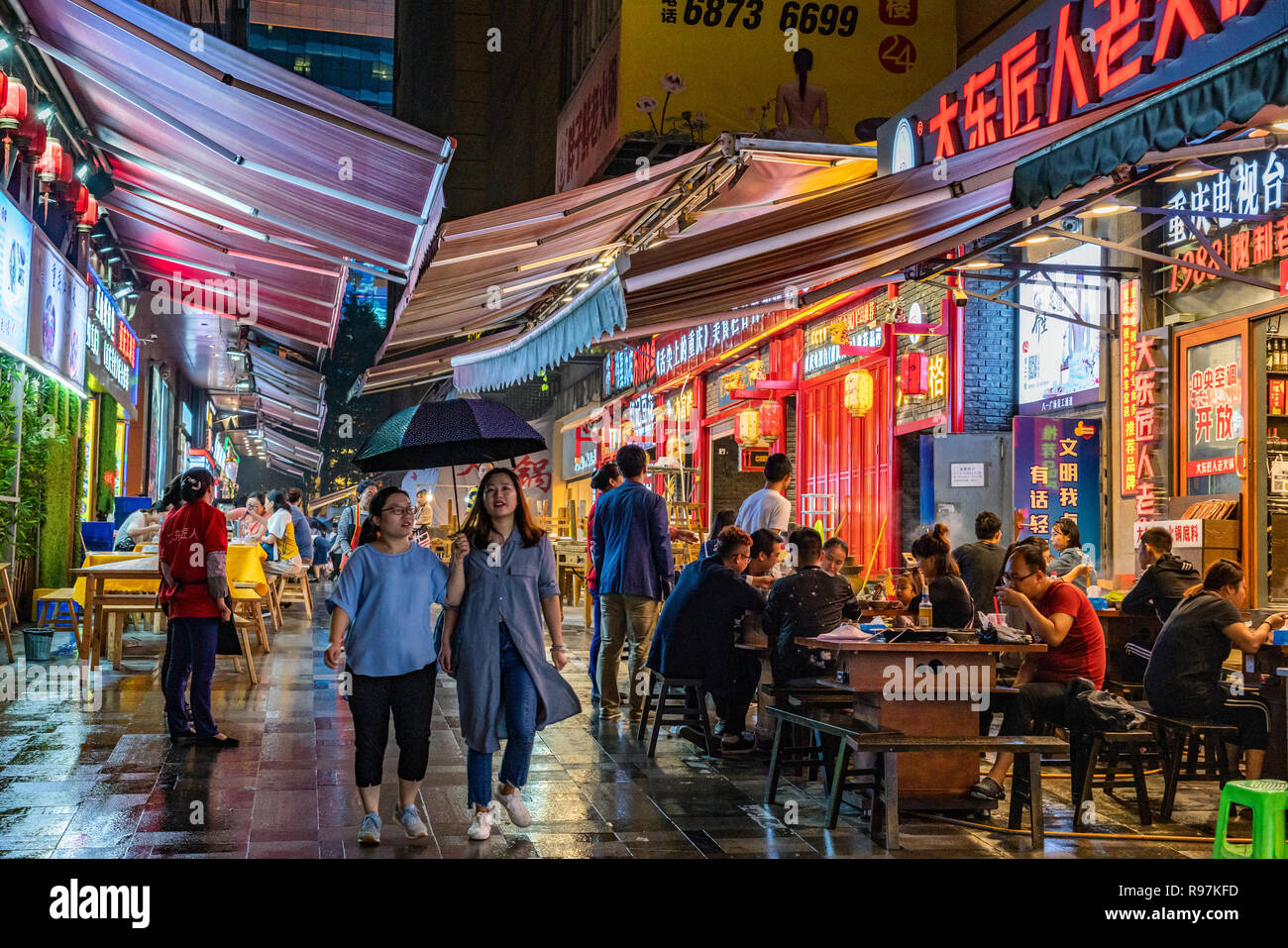 Scène de nuit d'une rue animée avec des restaurants locaux et de stands