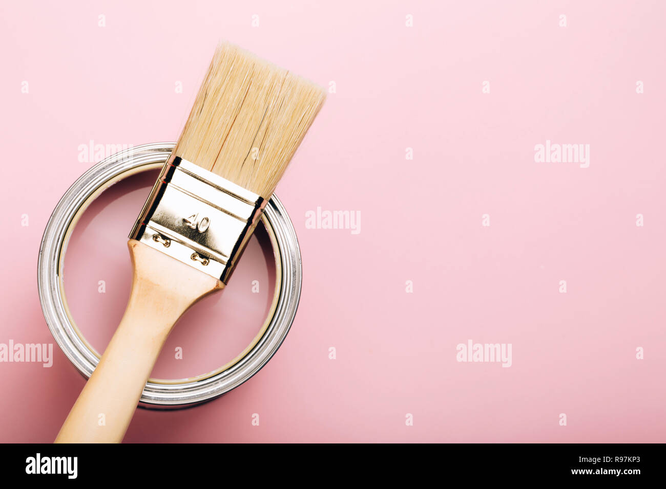 Brosse avec poignée en bois sur ouvert peut de peinture rose sur fond pastel. Concept de rénovation. Macro. Banque D'Images
