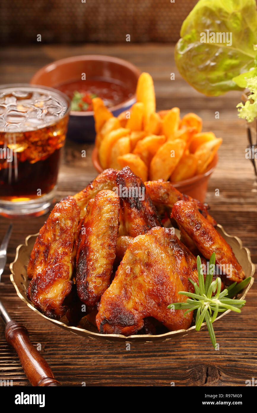 Hot Wings de poulet avec pommes de terre au four et sauce barbecue sur fond  de bois Photo Stock - Alamy