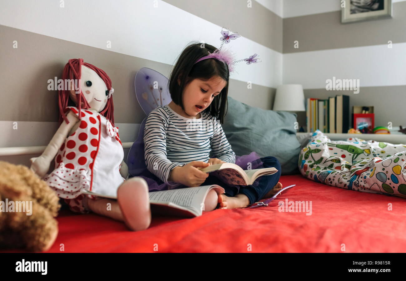 Déguisée de fille lire un livre à sa poupée Banque D'Images
