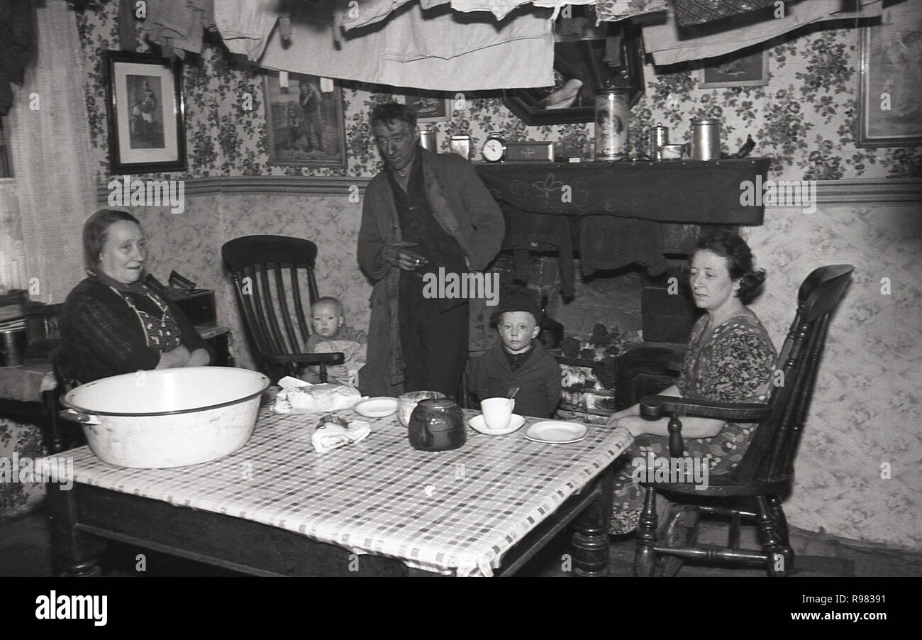 1940, un travailleur de mine de charbon et sa famille autour de la cheminée, une tasse de thé à la maison dans la chambre à l'avant à Merthyr, au Pays de Galles. Banque D'Images