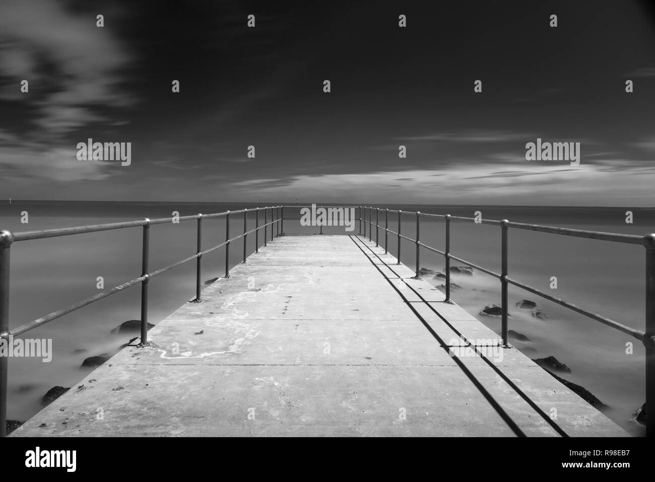 Jetty menant dans la baie, éclairé par la lune, la nuit, l'exposition ling B&W Banque D'Images