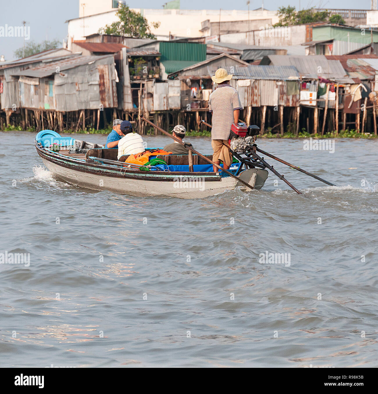Trois touristes masculins étant prises par les petits bateau à moteur pour visiter le célèbre marché flottant de Cai Rang, Cai Rang,la rivière Can Tho Province, Vietnam Banque D'Images