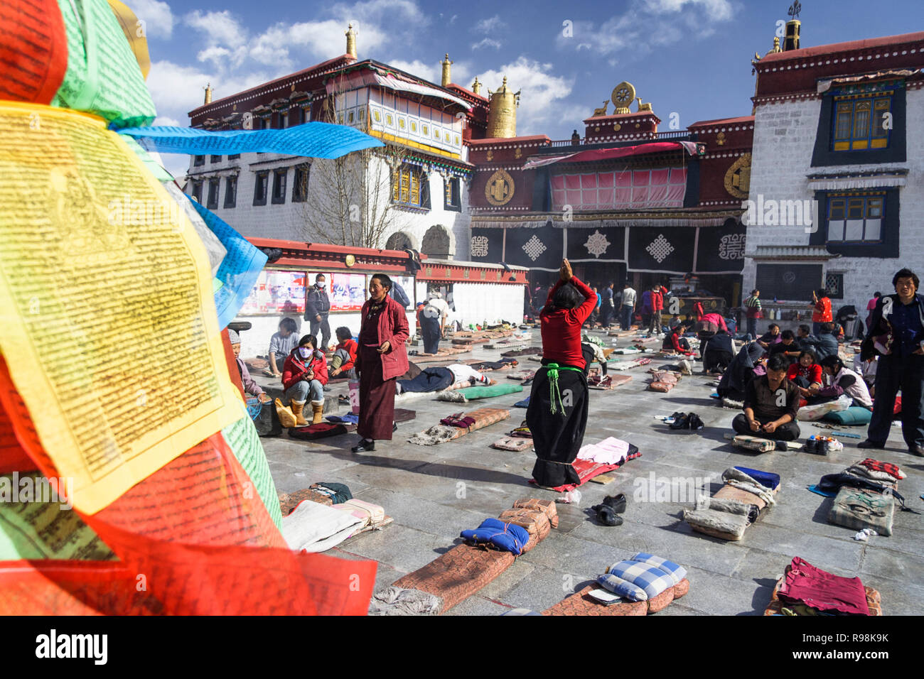 Lhassa, dans la région autonome du Tibet, Chine : pèlerins bouddhistes tibétains postrate et prier par le temple de Jokhang dans quartier du Barkhor. Le Jokhang est considéré comme Banque D'Images