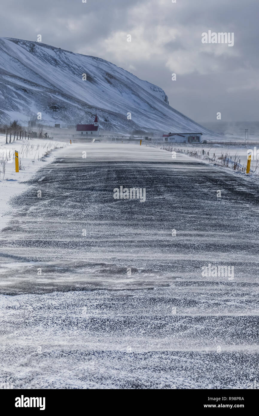 La conduite en hiver, avec la tempête de neige et les conditions dangereuses, avec l'Église Reyniskirkja Reynisfjara qui jouit de la route menant à la plage de sable noir près de Vik en Islande Banque D'Images