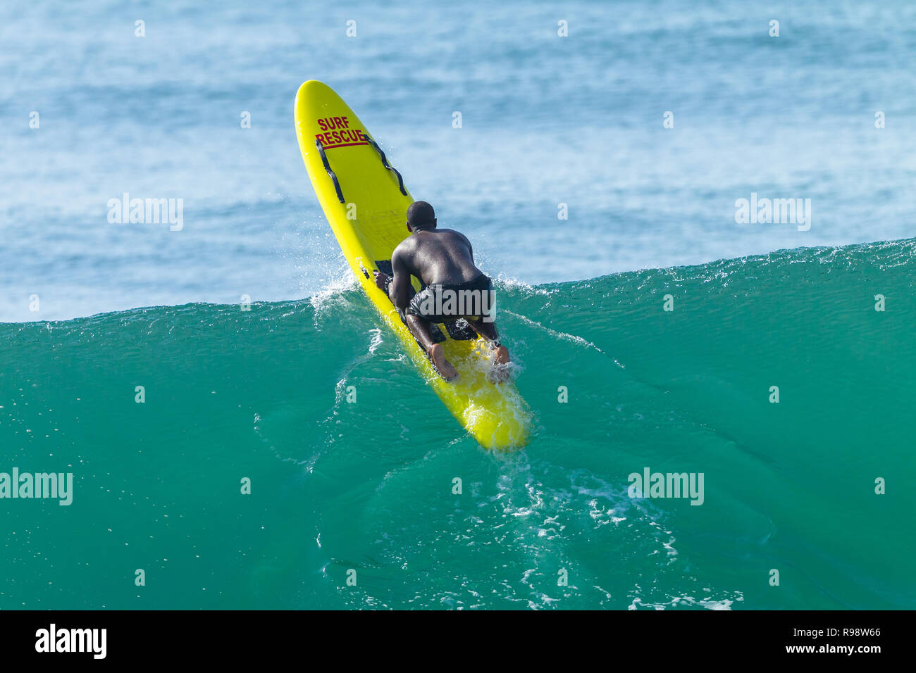Lifeguard pagayage homme africain noir océan de vague plus backline jaune sur l'embarcation de sauvetage de surf. Banque D'Images