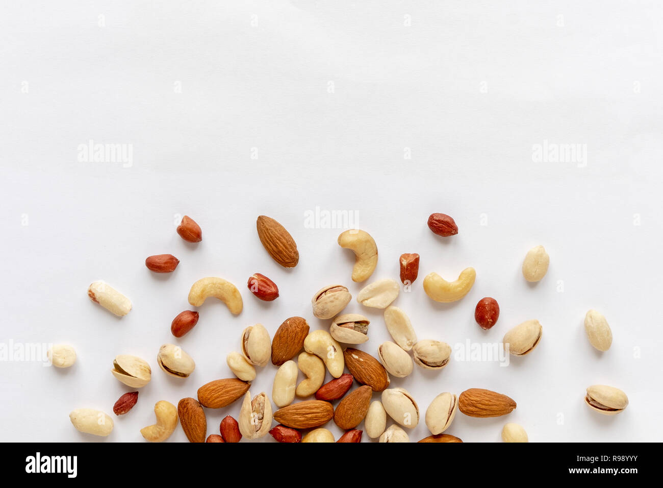 Un assortiment de noix rôties et dispersés sur blanc aux amandes, arachides, arachides, pistaches et noix de cajou vue dans une mise à plat de la vie toujours avec copie s Banque D'Images