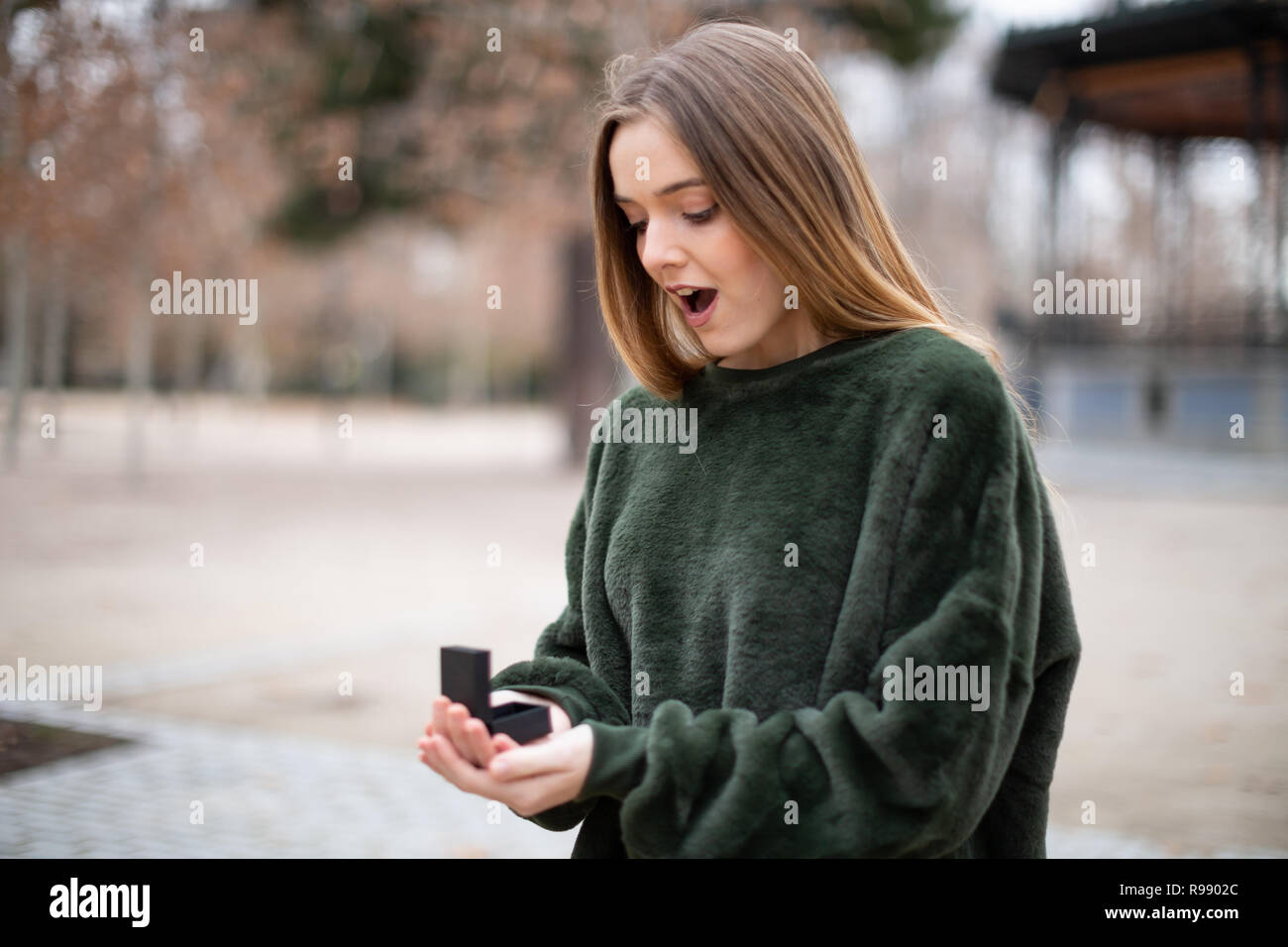 Belle jeune femme en costume élégant à la recherche à l'anneau de mariage dans la région de fort en se tenant sur le flou Banque D'Images