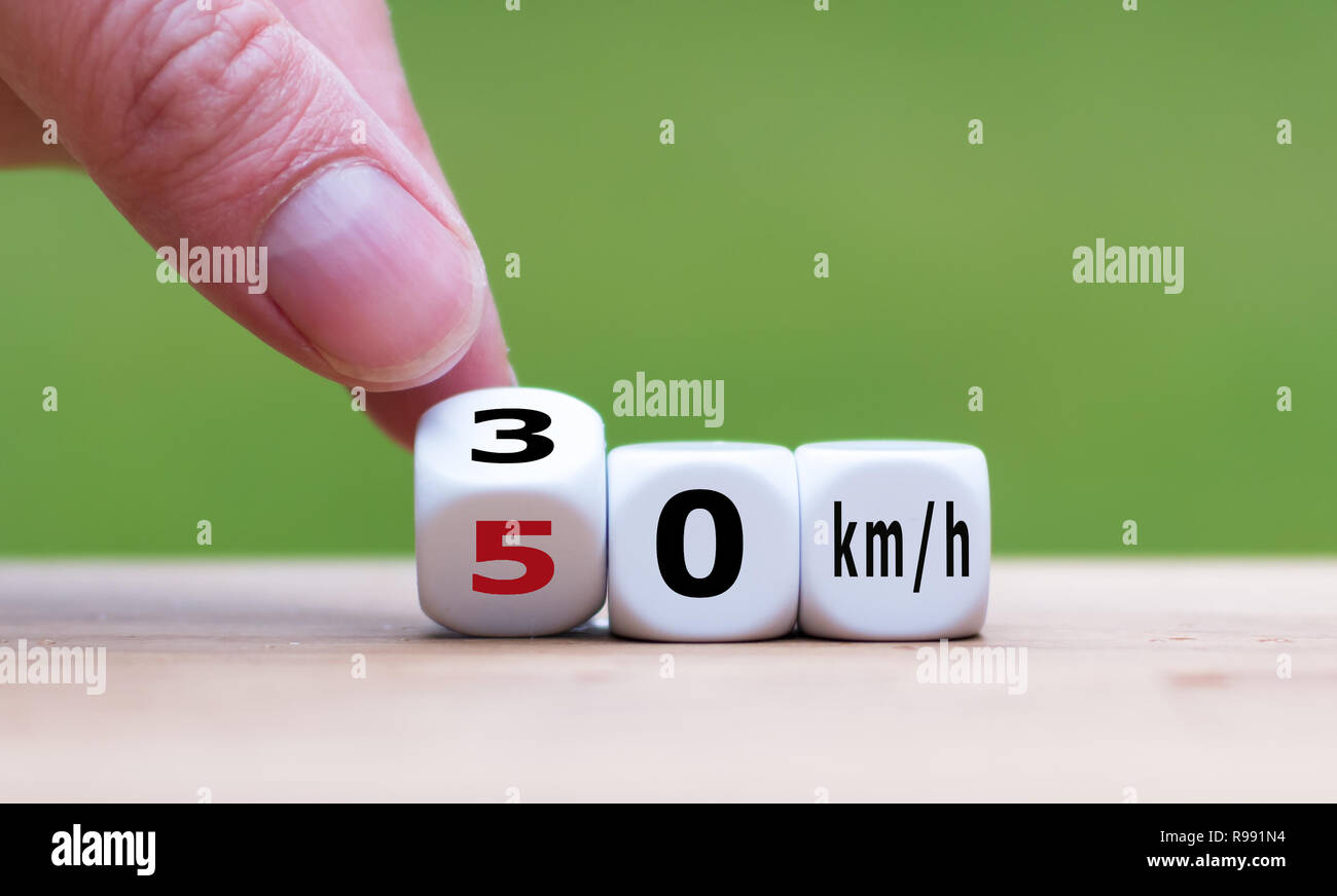 La main est le tournant d'un dés et change la expression "50 km/h" à "30 km/h' comme symbole pour réduire la limite de vitesse de 50 à 30 kilomètres par heure Banque D'Images