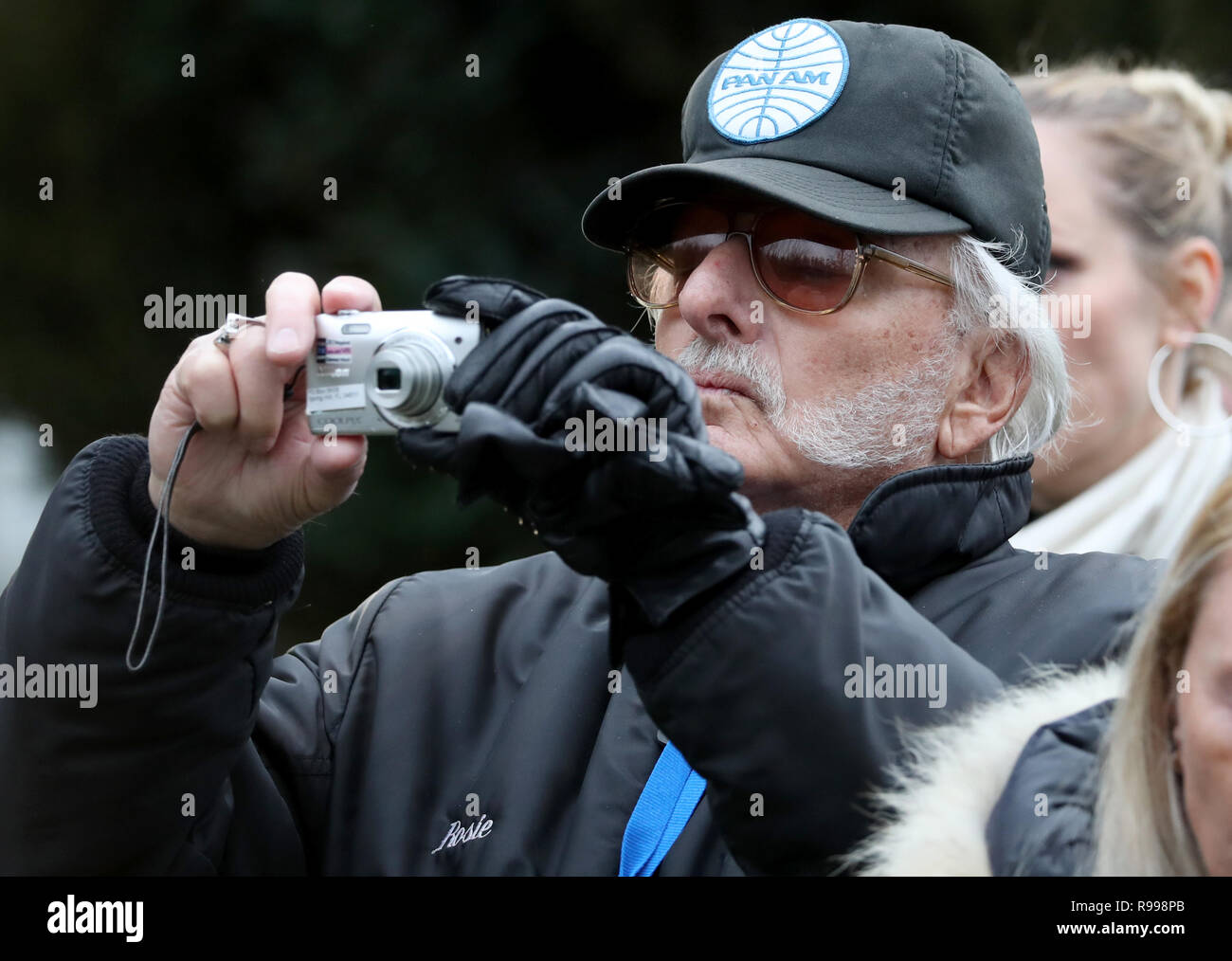 Un homme prend une photo que les gens se rassemblent pour rendre hommage au service commémoratif pour marquer le 30e anniversaire de l'attentat de Lockerbie, le Jardin du Souvenir au Cimetière Dryfesdale, Lockerbie. Banque D'Images