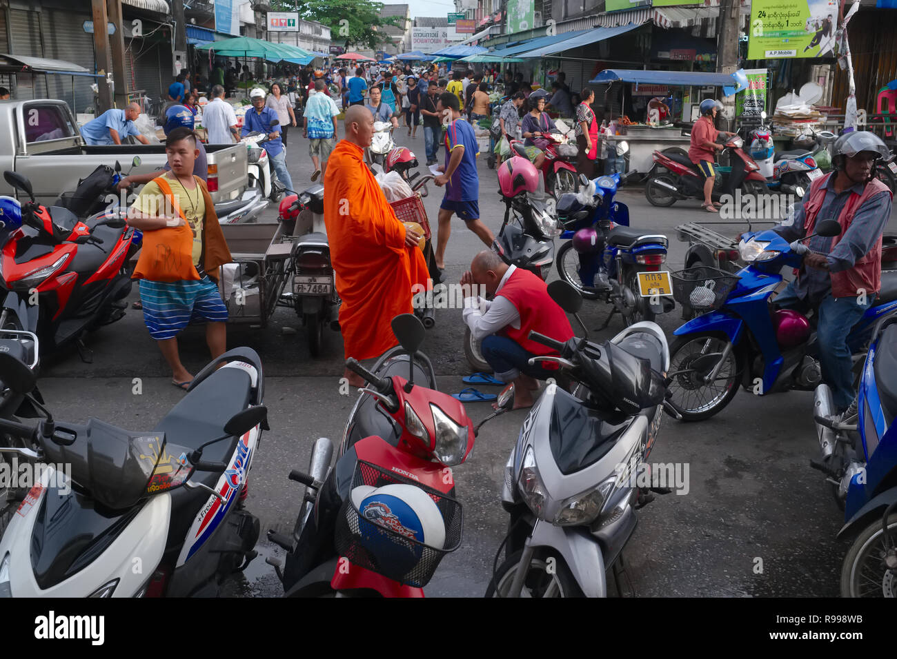 Un chauffeur de taxi moto sur le marché principal de la ville de Phuket, Thaïlande, arcs à un moine bouddhiste et présente ses respects à un cadre thaïlandais traditionnel 'wai' Banque D'Images