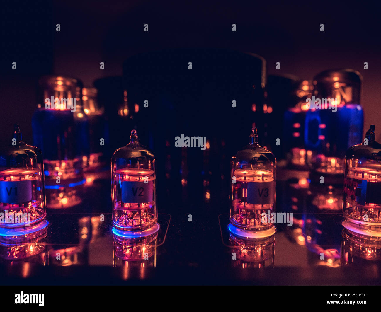 Tubes à vide sur une ligne, brillants dans l'obscurité. Contraste des couleurs chaudes une lueur bleue. Banque D'Images