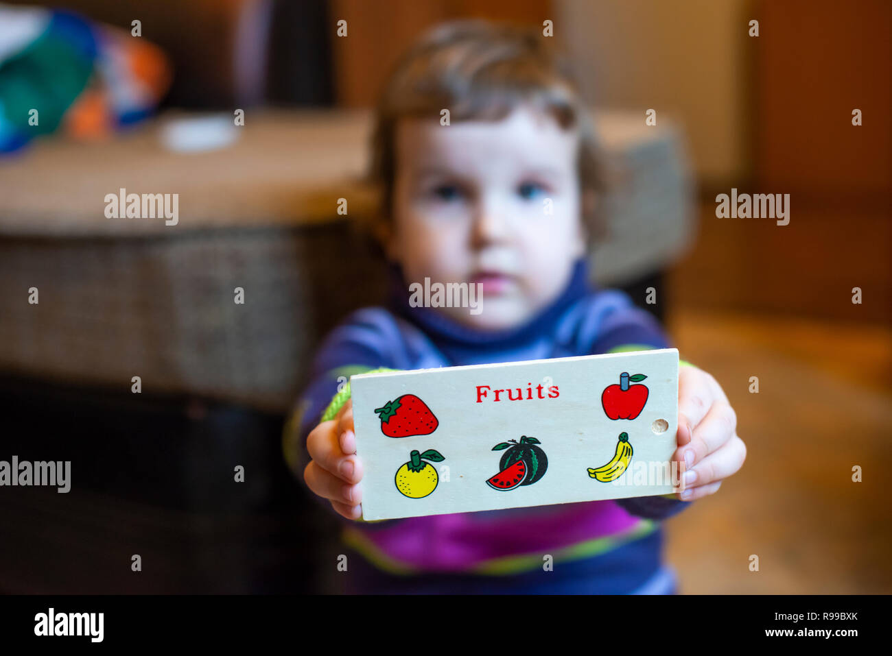 Petite fille du spectacle avec des fruits peints sur elle. Enfant jouant avec des fruits en bois jouet. La saine alimentation La métaphore conceptuelle avec fruits peints. Banque D'Images