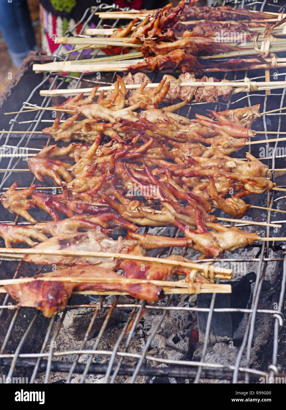 Poulet et de Lao grillées sur un outdoorcharcoal pieds grill Banque D'Images