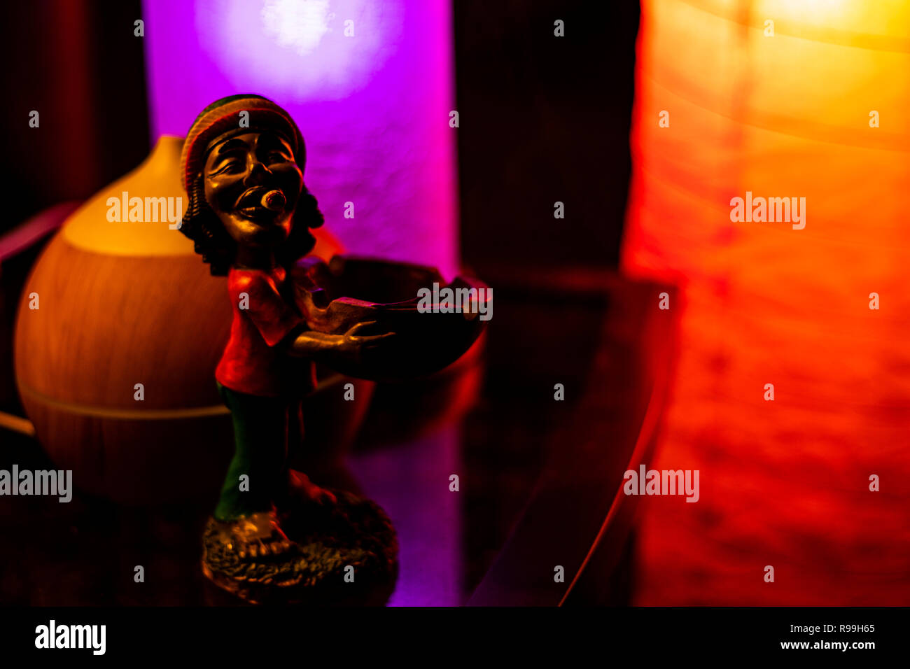 Bob Marley figurine on reflective bureau en verre par un diffuseur à huile allumé par 2 lampes LED. Banque D'Images